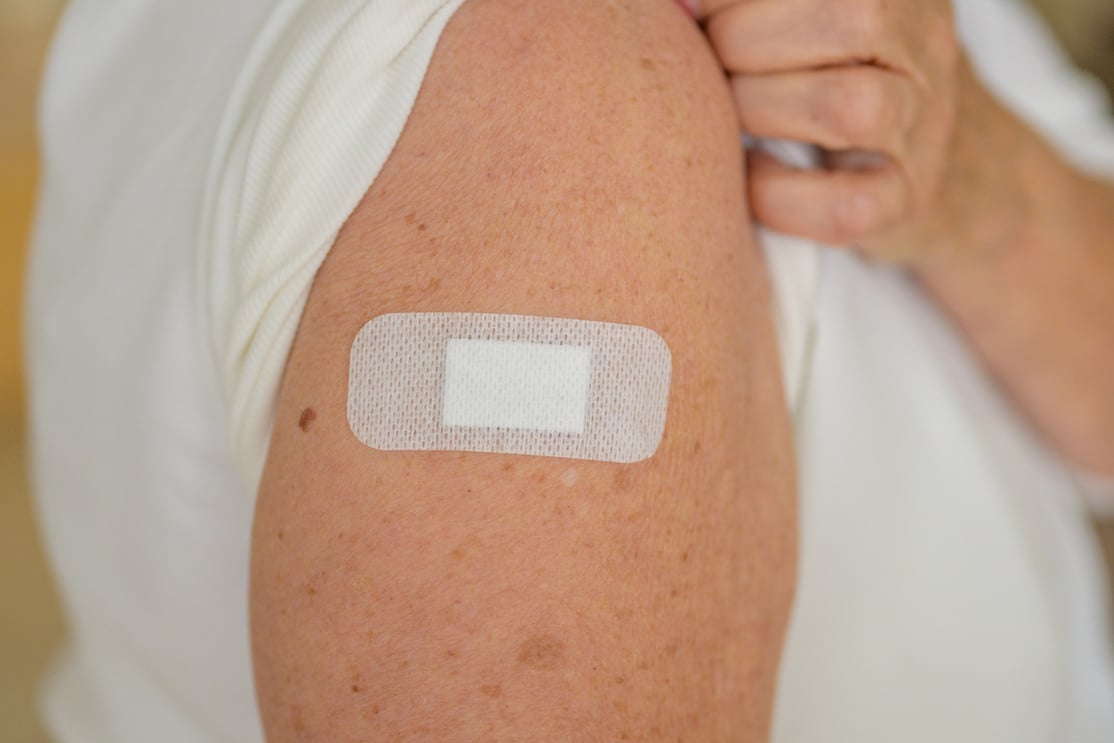 Anonymous lady showing the plaster covering her vaccination site